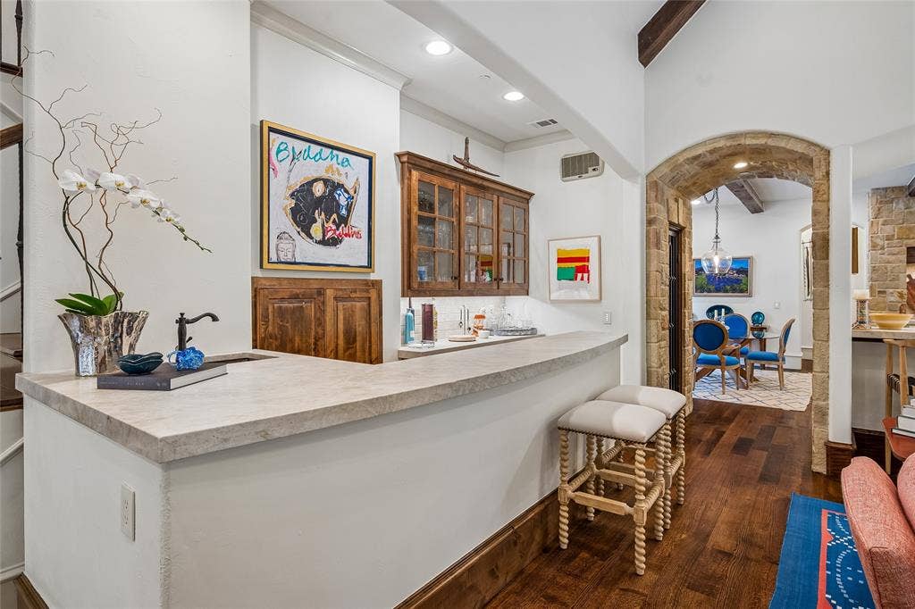 5222 Stonegate Road, Dallas, TX 75209 Wet bar with stone-finish countertop, wood-finish cabinetry, and a dark-finish faucet