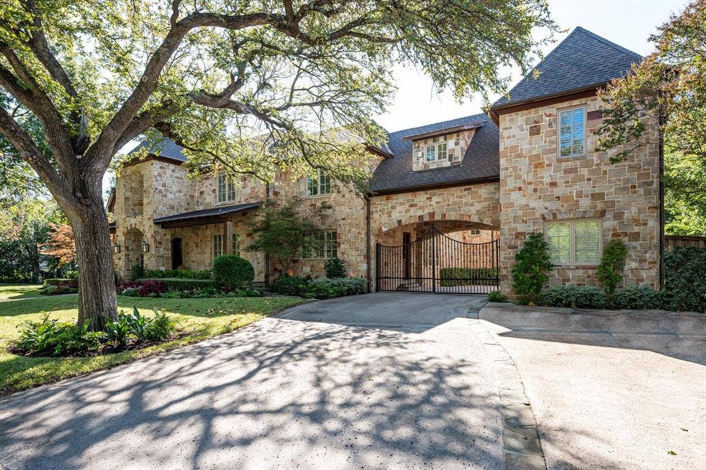 5222 Stonegate Road, Dallas, TX 75209 Stone exterior façade featuring a multi-gabled roofline, arched portico, gated motor court, and mature landscaping