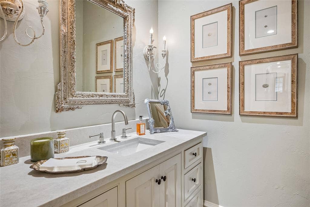 5222 Stonegate Road, Dallas, TX 75209 Just one of 8 bathrooms, this powder room offers white vanity with recessed panel cabinet doors and drawers, undermount rectangular sink, light-toned countertop, and a decorative mirror