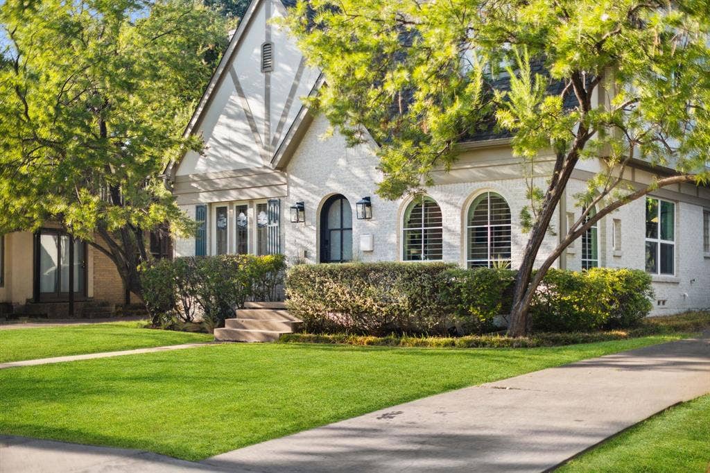 5709 Kenwood Avenue, Dallas, TX 75206 Tudor-style architecture featuring a prominent gable, arched entry, decorative stucco facade, and established landscaping