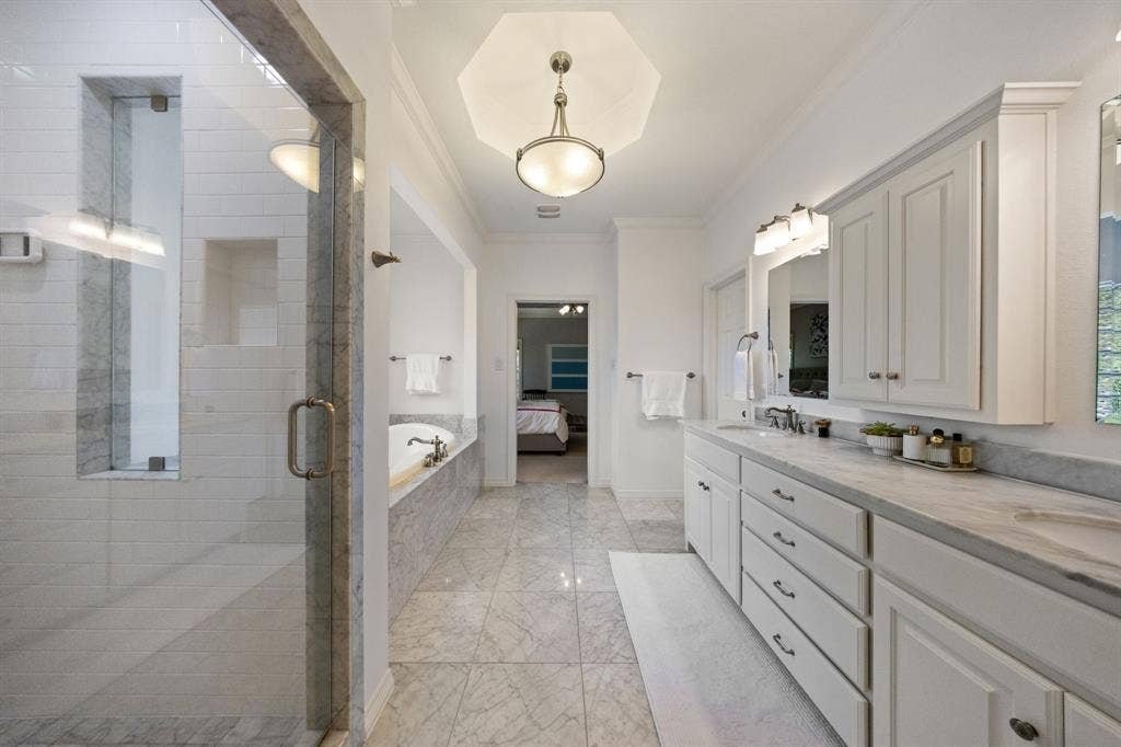 5709 Kenwood Avenue, Dallas, TX 75206 Elongated bathroom featuring a glass-enclosed shower, built-in soaking tub, dual vanity with undermount sinks, and integrated cabinetry