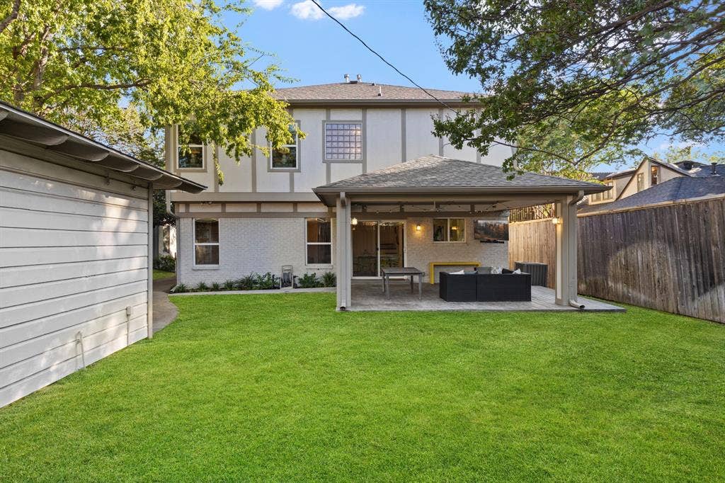 5709 Kenwood Avenue, Dallas, TX 75206 Expansive green lawn, covered patio area, stucco exterior, privacy fencing, and a detached structure