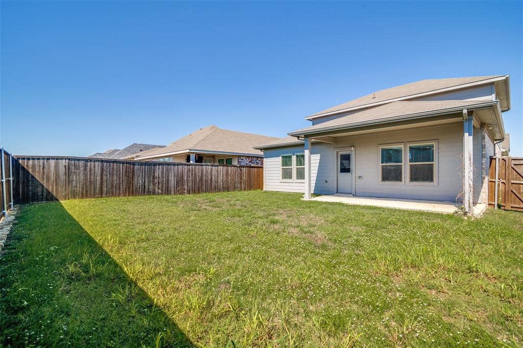 2403 Rocky Mountain Drive, Royse City, TX 75189 Expansive backyard with a covered patio, wood privacy fencing, and multiple exterior windows