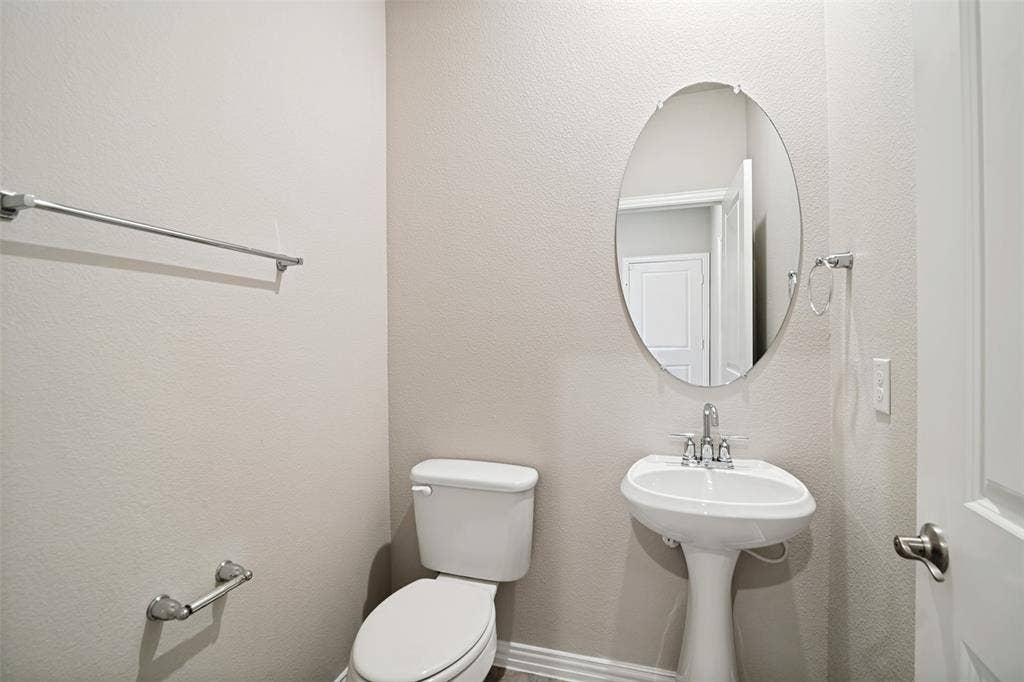 2403 Rocky Mountain Drive, Royse City, TX 75189 Pedestal sink with chrome faucet, oval mirror, and white toilet