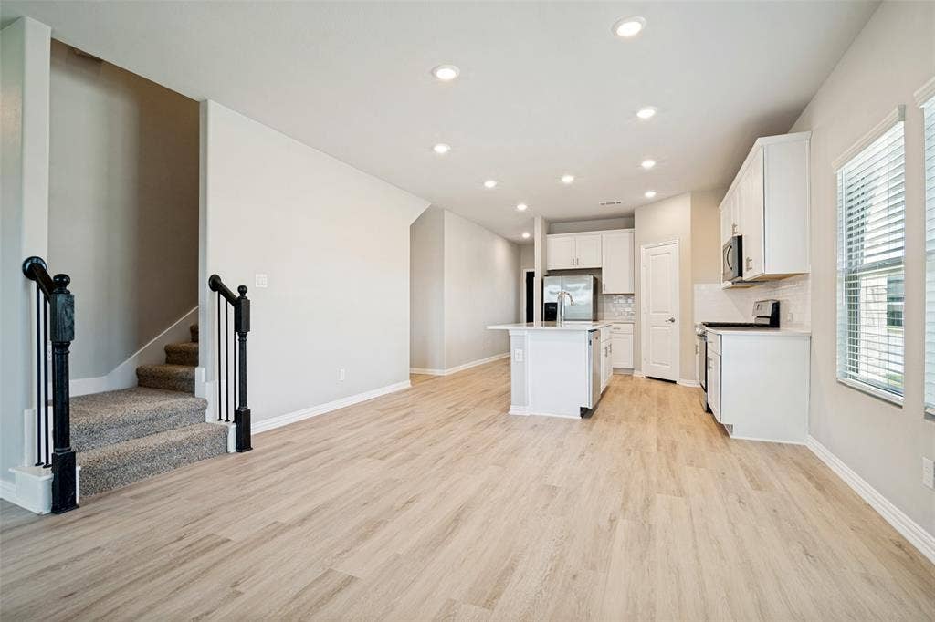 2403 Rocky Mountain Drive, Royse City, TX 75189 Open-concept living area featuring wood-finish flooring, recessed lighting, and a kitchen with white cabinetry