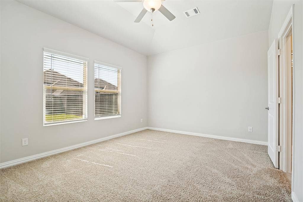 2403 Rocky Mountain Drive, Royse City, TX 75189 Two windows with blinds, neutral carpet, ceiling fan with light, and white paneled door