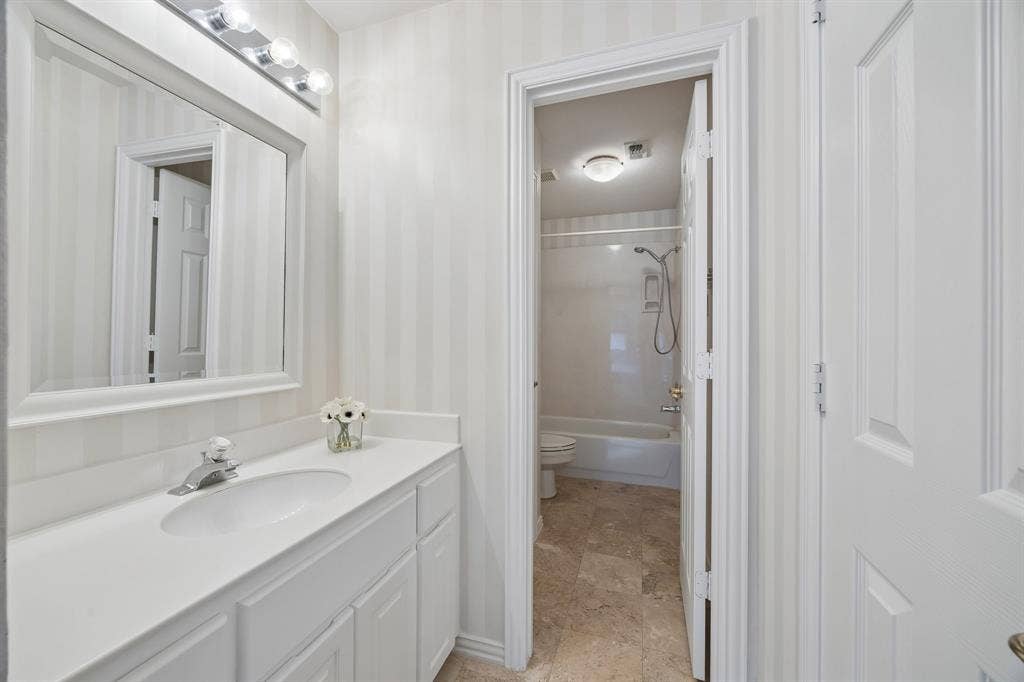 1106 Hills Creek Drive, McKinney, TX 75072 Vanity area of the jack and jill bathroom looking through to the shared watercloset with tub with shower.