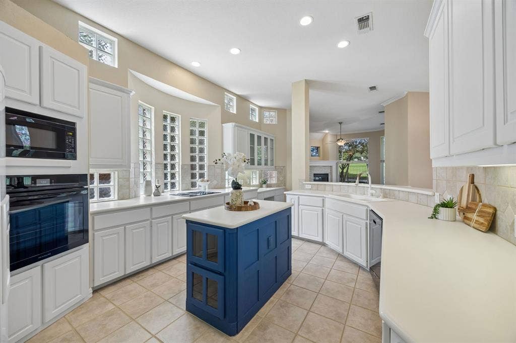 1106 Hills Creek Drive, McKinney, TX 75072 The kitchen is quite large and provides ample storage and counter space. The center island has additional storage, bins for vegetables and shelves on the opposite side. The kitchen has corian countertops, 42in upper cabinets and black appliances complete.