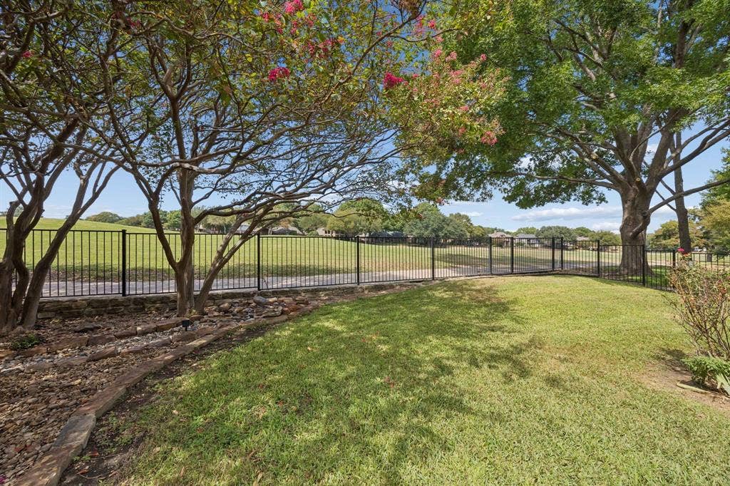 1106 Hills Creek Drive, McKinney, TX 75072 Looking from the flagstone pathway across the yard to the golf course and walking path behind the home. There is a gate in the fence that leads to the walking path.