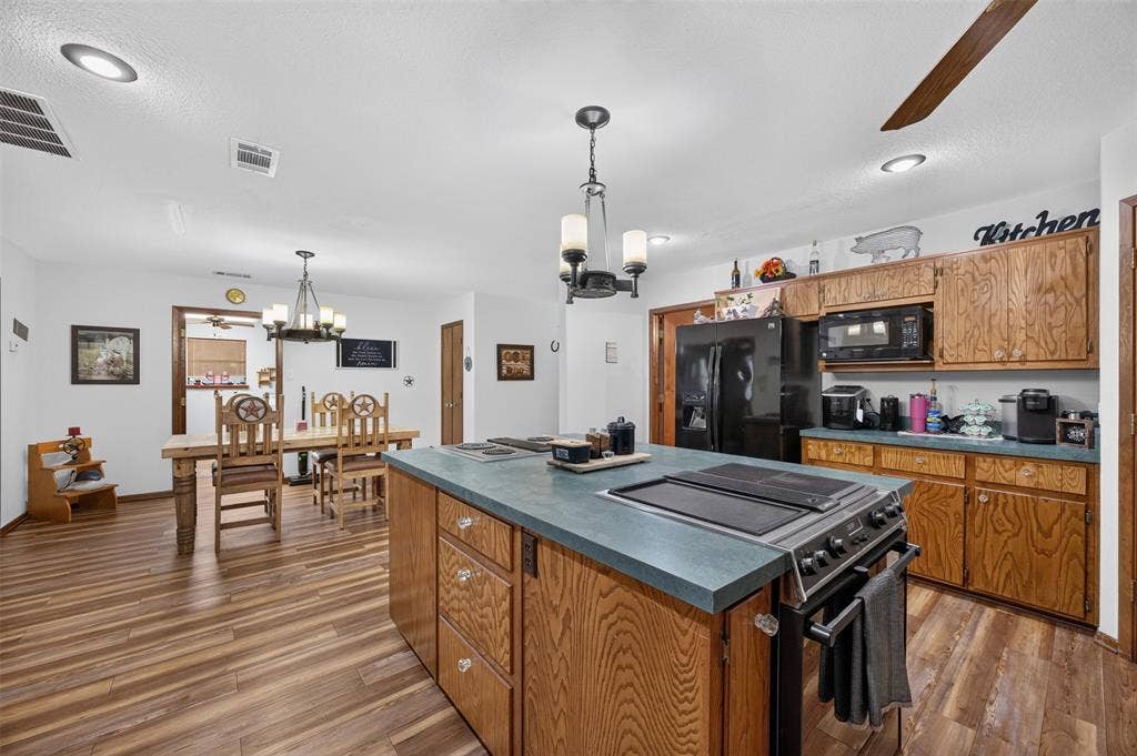 Kitchen island with cooktop, wood-finish flooring, wood cabinetry, and recessed lighting