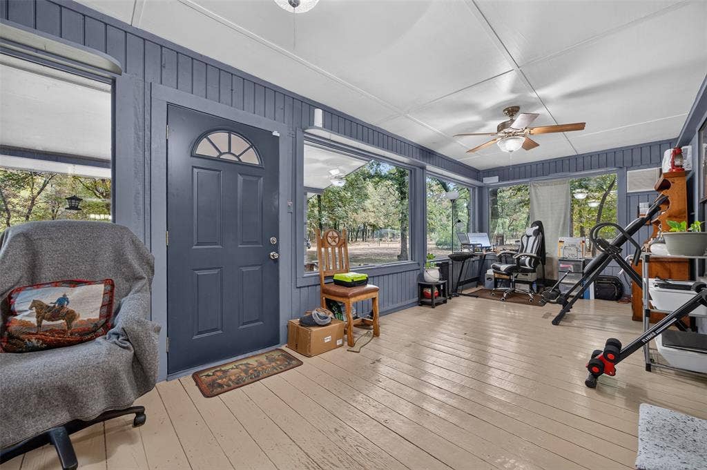 Enclosed porch featuring wood-finish flooring, wood paneling, and an exterior door with an arched window insert