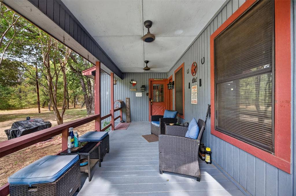 Covered front porch with slatted siding, a wood-paneled door with glass inserts, and overhead ceiling fans