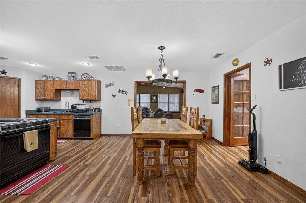 Wood-finish flooring throughout, with a kitchen featuring wood cabinetry and a stainless steel sink