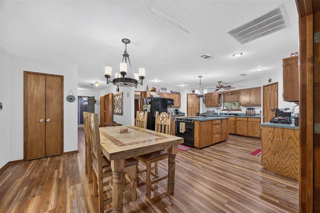 Wood-finish flooring throughout, kitchen with wood cabinetry, and a ceiling fan
