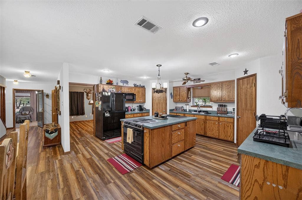 Kitchen featuring wood-finish flooring, wood cabinetry, a center island with countertop, and recessed lighting