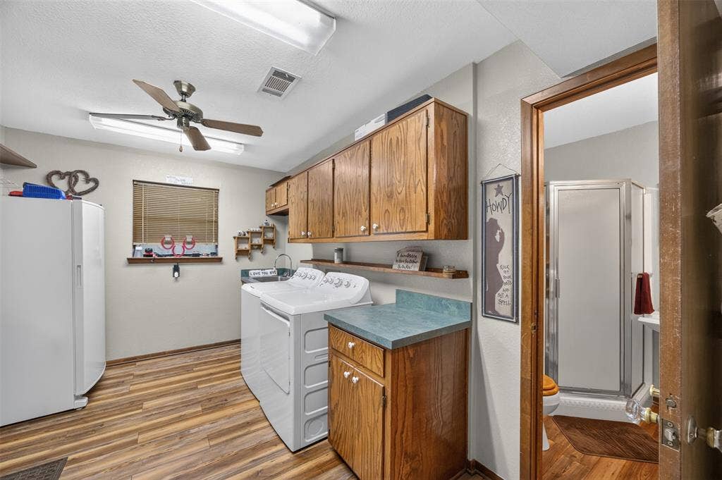 Wood-finish flooring throughout, ceiling fan with integrated lighting, and wood cabinetry offering ample storage