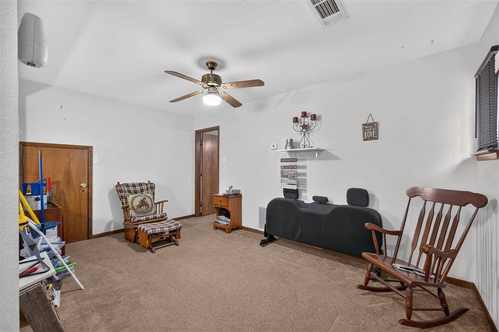 Carpeted flooring, white painted walls, wood-finish interior doors, and a ceiling fan with integrated lighting