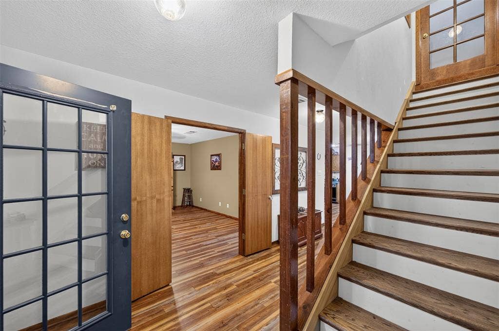 Wood-finish flooring throughout, wood staircase with white risers, and a wood handrail