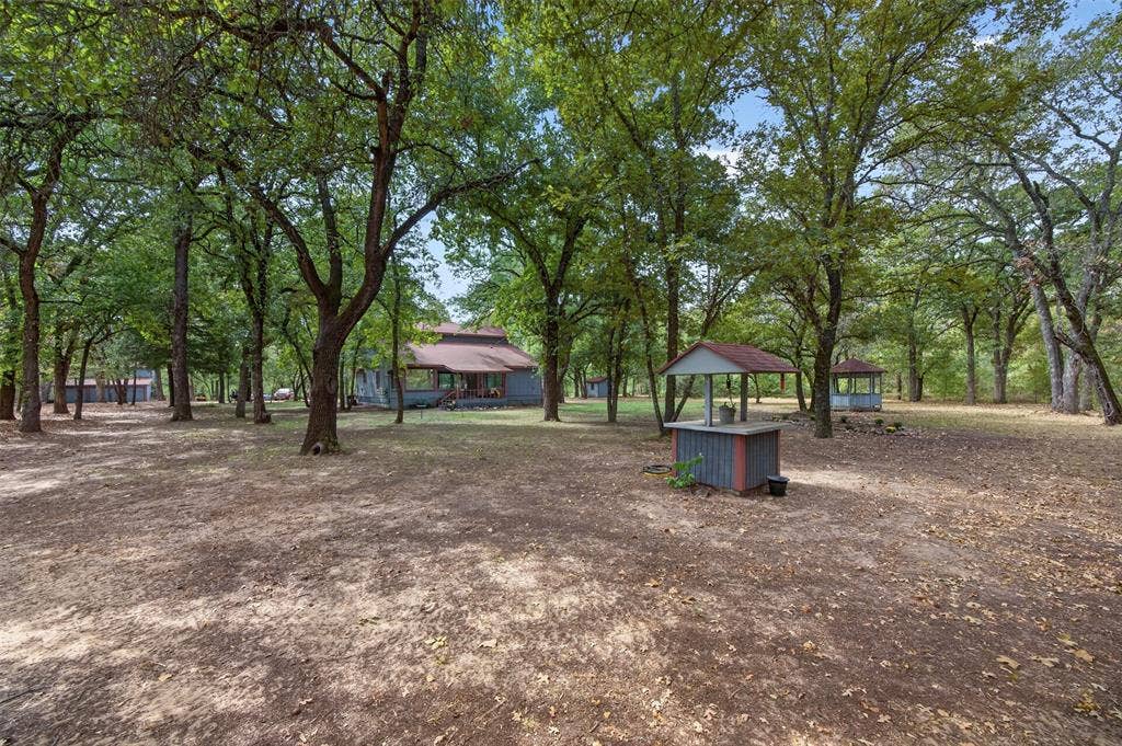 Extensive tree coverage, multiple outbuildings, well structure, and a main residence with a covered porch