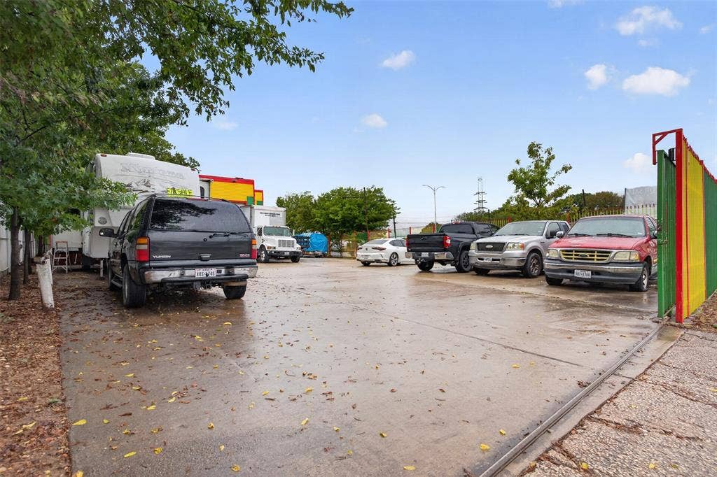 2301 S Denley Drive, Dallas, TX 75216 Paved parking area featuring a colorful gate and surrounding trees