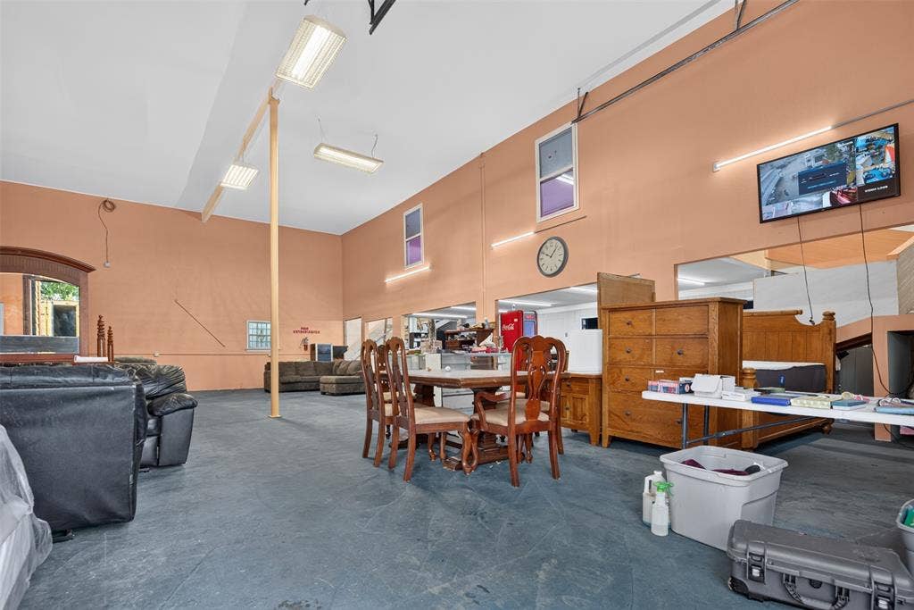 2301 S Denley Drive, Dallas, TX 75216 High ceilings with exposed structural elements, fluorescent lighting fixtures, and a wall-mounted clock