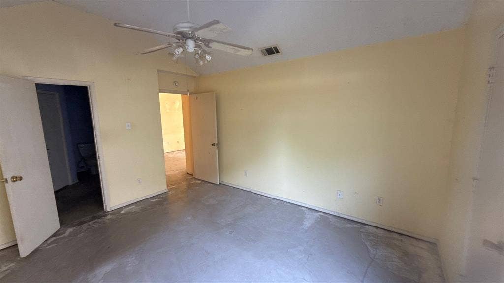 Spacious room with light-colored walls and a ceiling fan