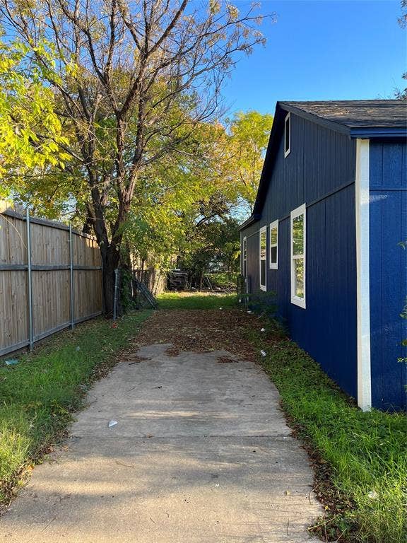 3806 Pine Street, Dallas, TX 75210 Exterior side yard featuring a concrete path, wood-panel siding, and a wooden privacy fence