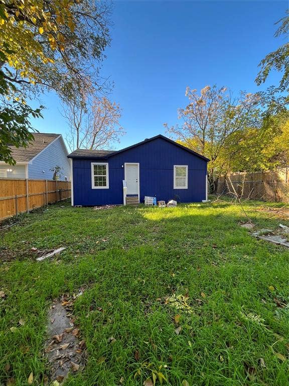 3806 Pine Street, Dallas, TX 75210 Rear exterior featuring vertical siding, two multi-pane windows, and wood-style perimeter fencing