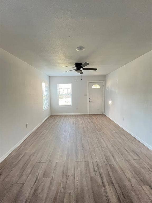 3806 Pine Street, Dallas, TX 75210 Neutral-toned room featuring wood-finish flooring, a ceiling fan with integrated lighting, dual windows, and an exterior door with a glass insert