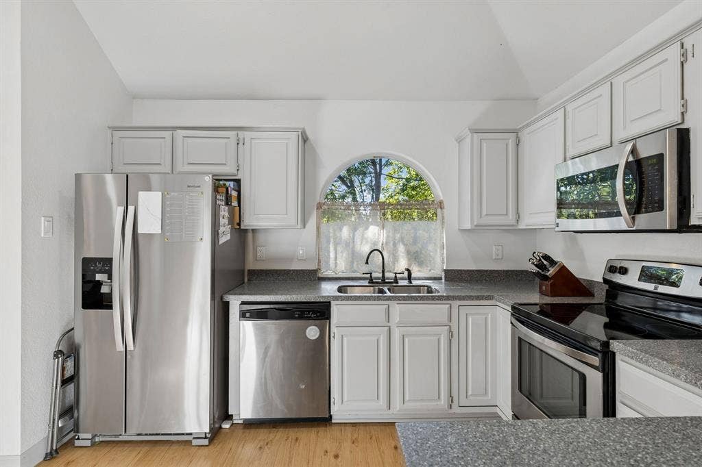 1111 Hyde Park Drive, McKinney, TX 75069 The lovely kitchen displays stainless steel appliances, recessed lighting, LVP flooring, vaulted ceilings, and smooth stone countertops.