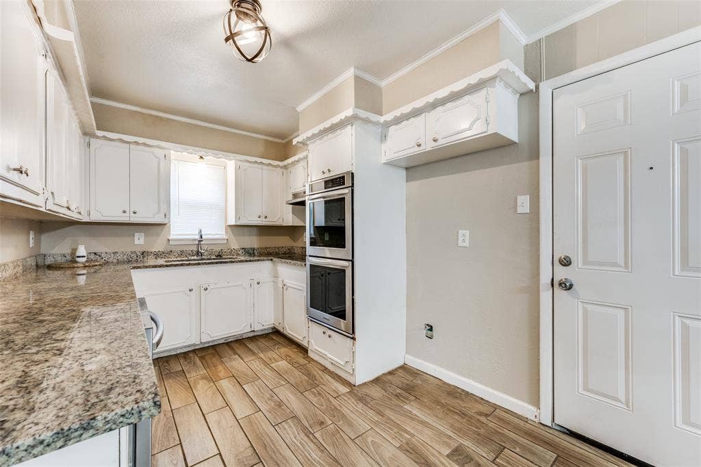 213 W Dorris Drive, Grand Prairie, TX 75051 Kitchen with white cabinetry, wood-finish flooring, light-toned countertops, and built-in double ovens