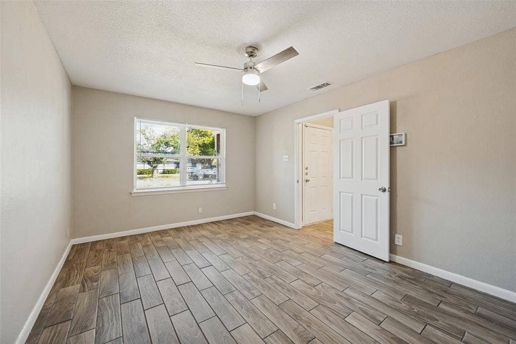 213 W Dorris Drive, Grand Prairie, TX 75051 Wood-finish tile flooring, ceiling fan with integrated lighting, and a large window with white trim