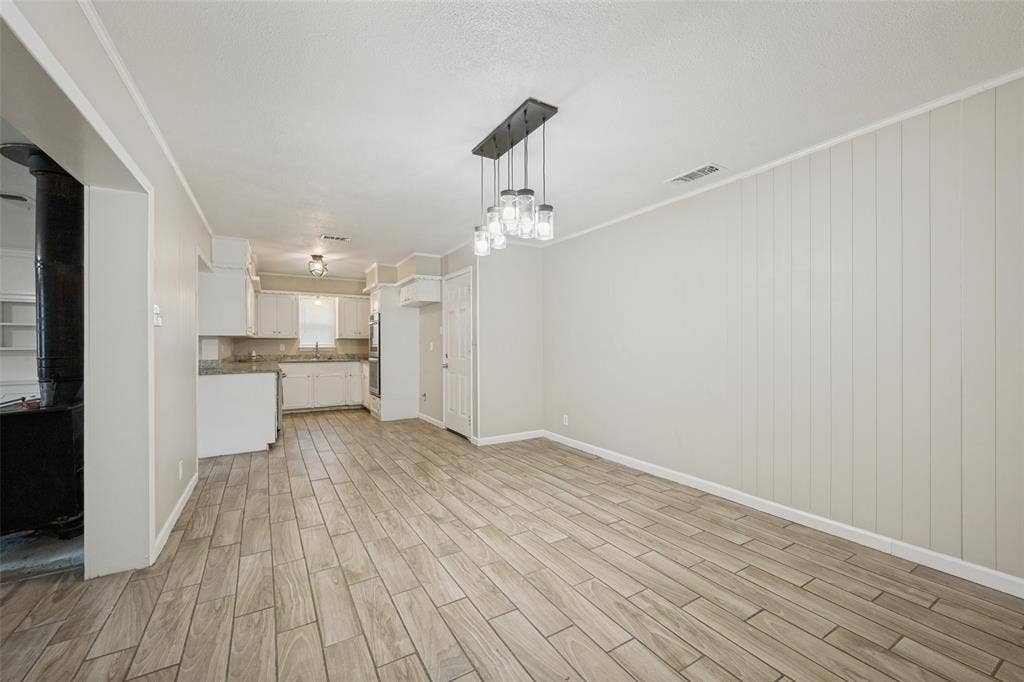 213 W Dorris Drive, Grand Prairie, TX 75051 Open-concept living area featuring wood-look tile flooring, a multi-light chandelier, and panel accent wall