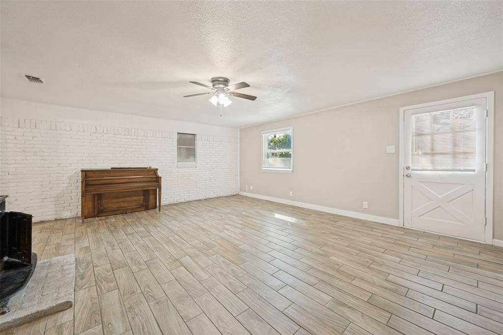 213 W Dorris Drive, Grand Prairie, TX 75051 Wood-finish flooring, white painted brick accent wall, ceiling fan, and a Dutch door with opaque glass panels
