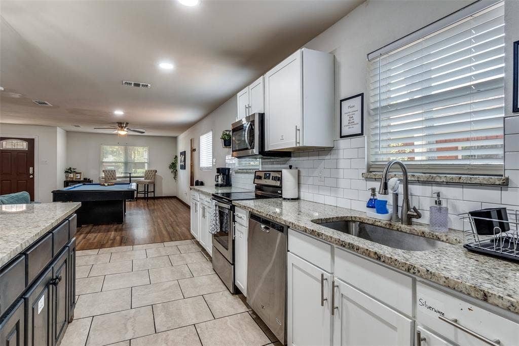 1816 Boyd Street, Dallas, TX 75224 Kitchen featuring granite countertops, white cabinetry, stainless steel appliances, and subway tile backsplash