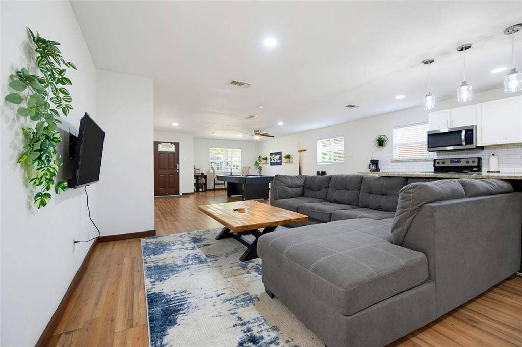 1816 Boyd Street, Dallas, TX 75224 Open-concept living area featuring wood-finish flooring, recessed lighting, and a kitchen with white cabinetry, stainless steel appliances, and pendant lighting