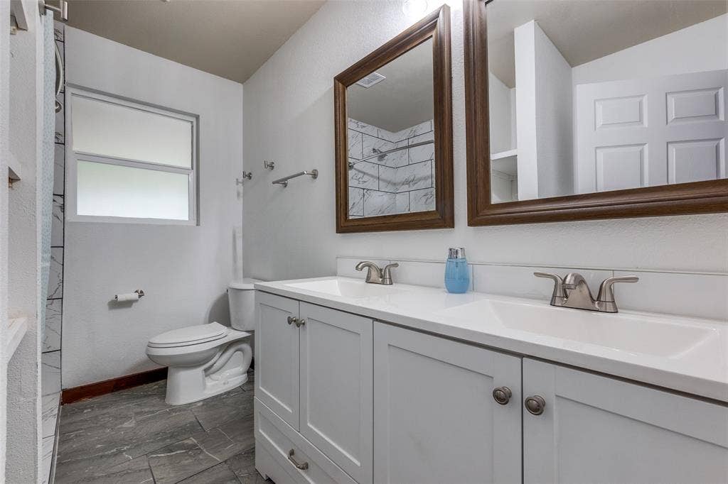 1816 Boyd Street, Dallas, TX 75224 Dual vanity with white cabinetry and integrated sinks, framed mirrors, and a window