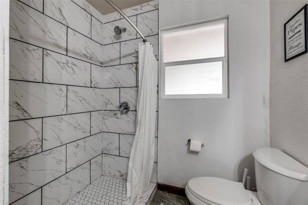 1816 Boyd Street, Dallas, TX 75224 Shower with white subway tile surround, hexagonal tile floor, and chrome fixtures
