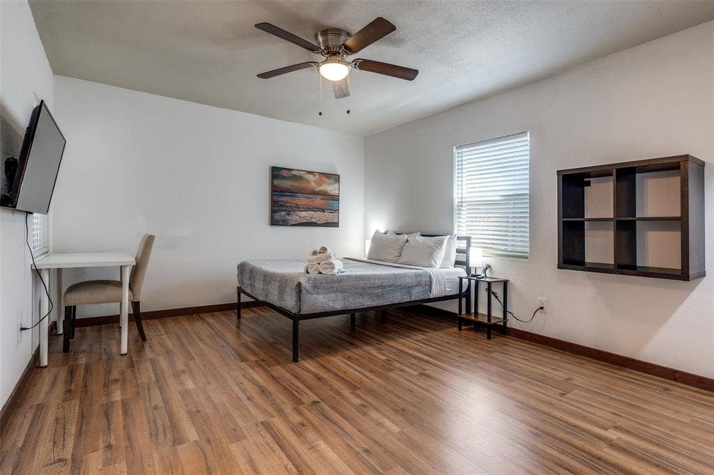 1816 Boyd Street, Dallas, TX 75224 Wood-finish flooring, ceiling fan with integrated lighting, wall-mounted shelving, and a window with blinds