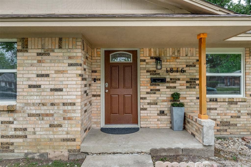 1816 Boyd Street, Dallas, TX 75224 Brick exterior with a covered entry, a wood panel door with an arched glass insert, and a decorative wall-mounted light fixture