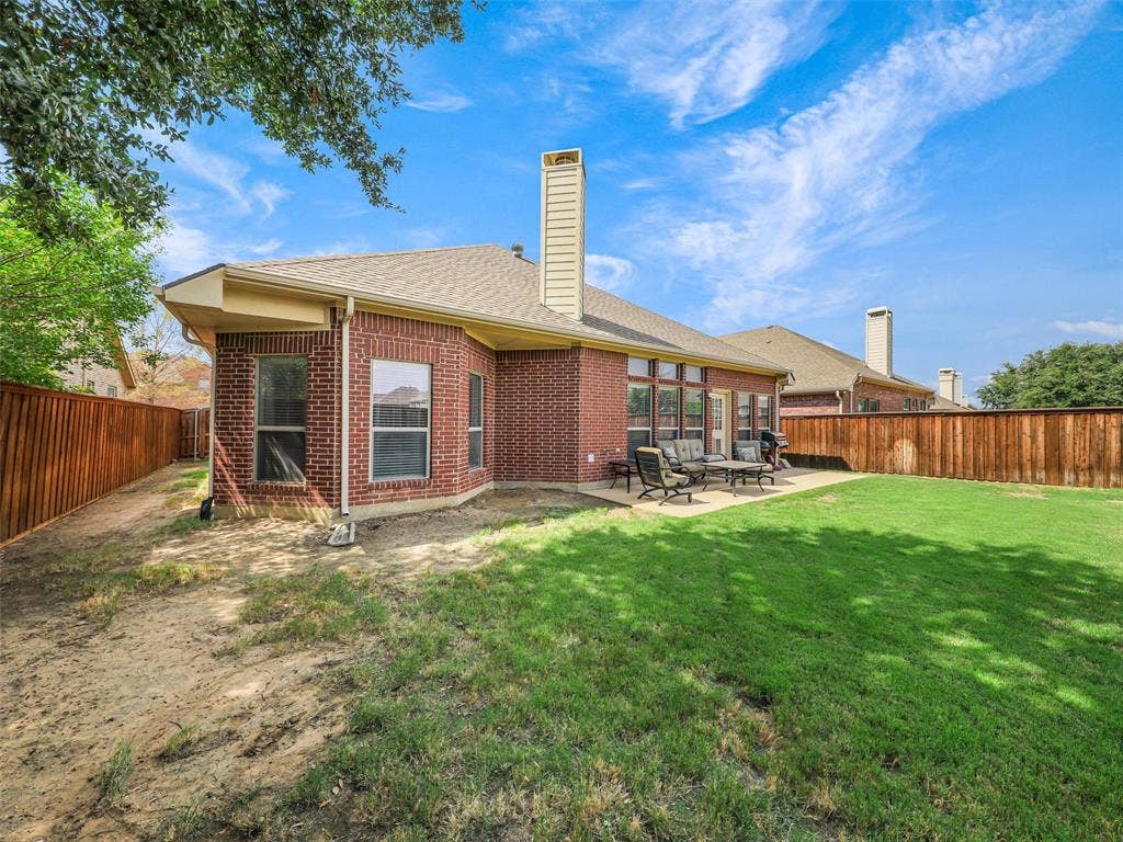 8374 Cain River Drive, Frisco, TX 75035 Rear brick exterior features large windows overlooking the backyard and a patio conveniently situated beside the home.