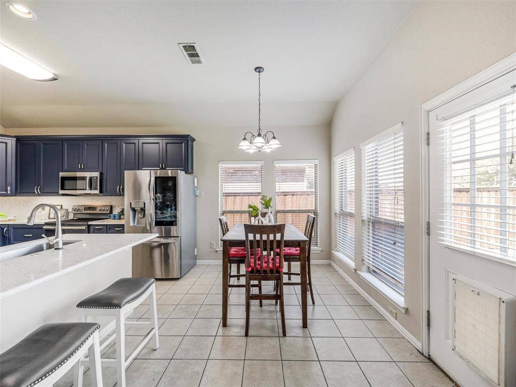 8374 Cain River Drive, Frisco, TX 75035 Bright breakfast nook features a decorative chandelier, surrounding windows, and convenient access to the backyard.