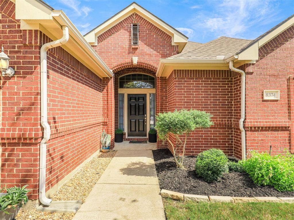 8374 Cain River Drive, Frisco, TX 75035 Covered front entry features door with side lights and a transom window for extra light and a landscaped walkway.