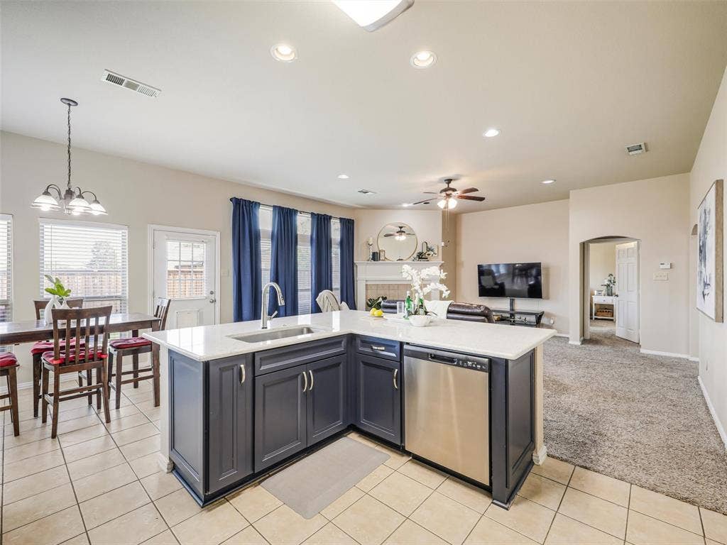 8374 Cain River Drive, Frisco, TX 75035 Kitchen peninsula features additional cabinet storage and a stainless steel dishwasher, with an open view of the breakfast nook and living room.