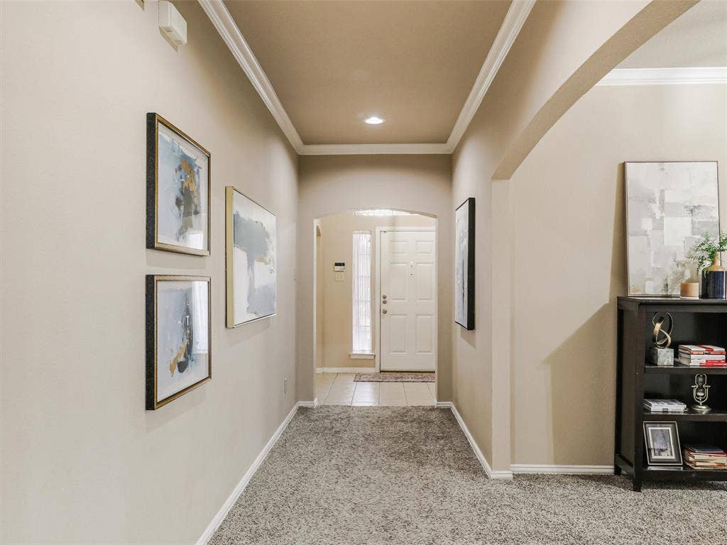 8374 Cain River Drive, Frisco, TX 75035 Crown molding, recessed lighting, and arched openings add character to the hallway connecting the front entry with the home’s interior.