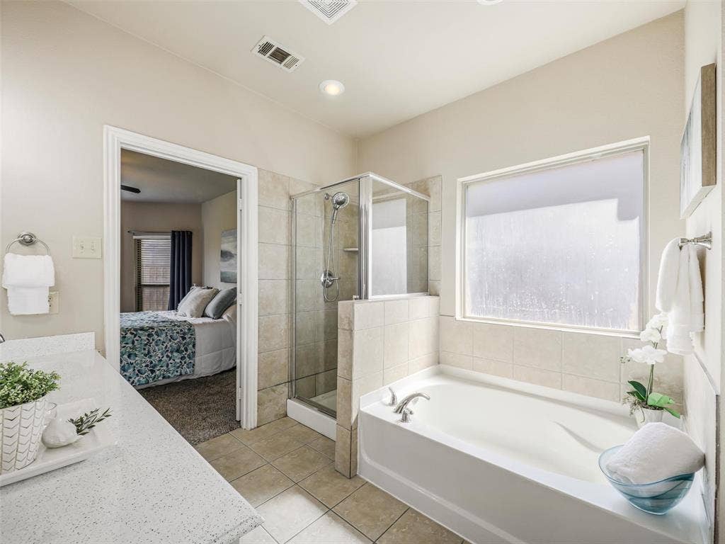 8374 Cain River Drive, Frisco, TX 75035 Relax in the soaking tub beneath a large privacy window, complemented by a separate glass-enclosed shower with tile surround.