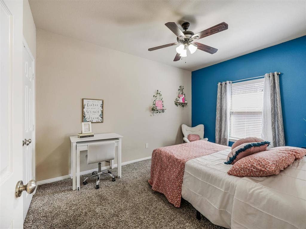 8374 Cain River Drive, Frisco, TX 75035 Spacious secondary bedroom features a blue accent wall, ceiling fan, and a window overlooking the front yard.