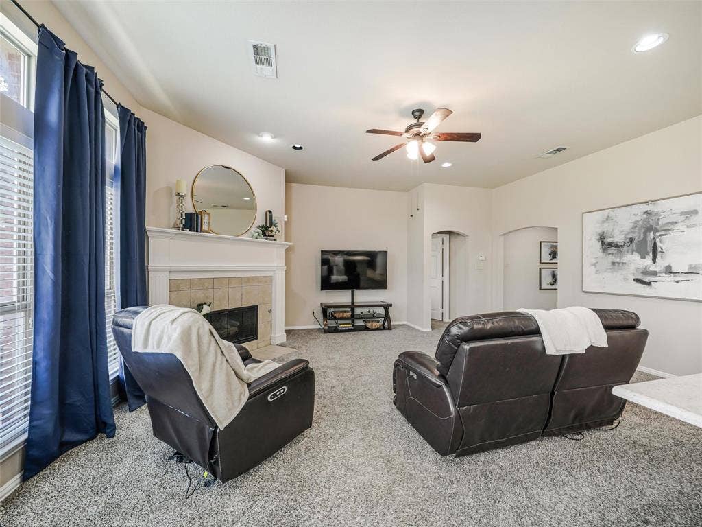 8374 Cain River Drive, Frisco, TX 75035 Large windows brighten this inviting living space, featuring a fireplace, generous seating area, and arched doorways leading to adjoining rooms.