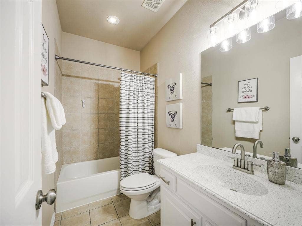 8374 Cain River Drive, Frisco, TX 75035 Full bathroom offers a white vanity, generous counter space, and a tub-shower combination with tile surround.