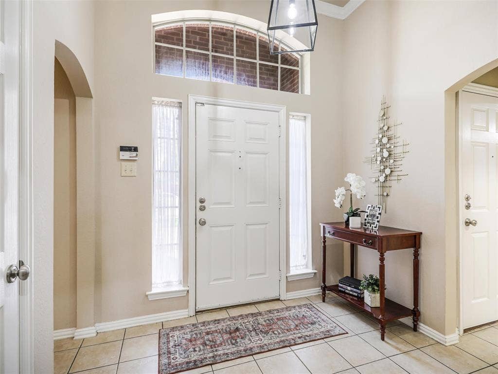 8374 Cain River Drive, Frisco, TX 75035 Welcoming foyer features tile flooring, a high ceiling, arched openings, and natural light through sidelights and a transom window.